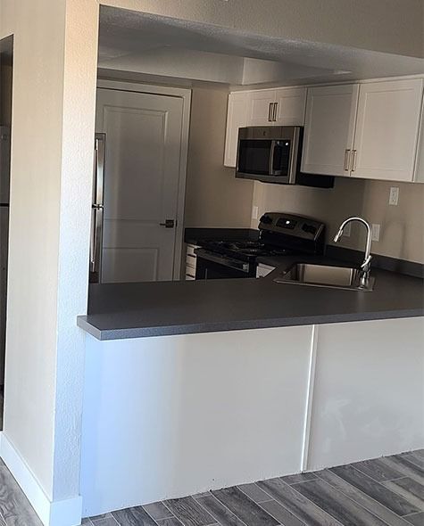 Kitchen with white cabinets, stainless steel appliances, and a gray countertop and backsplash.