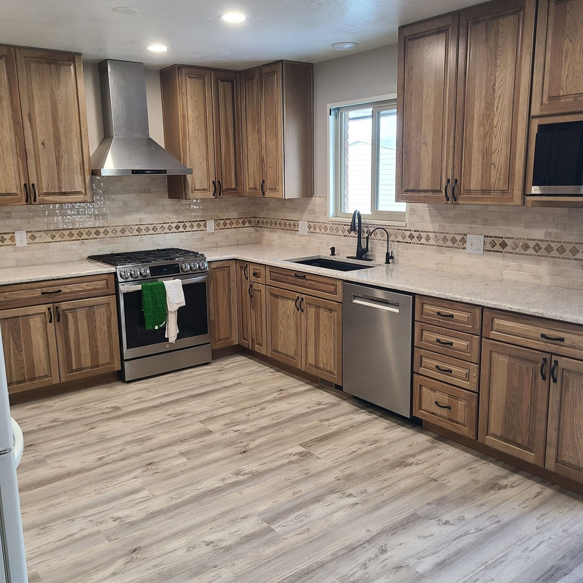 Kitchen with wood cabinets, stainless steel appliances, light countertops, and wood-look flooring.