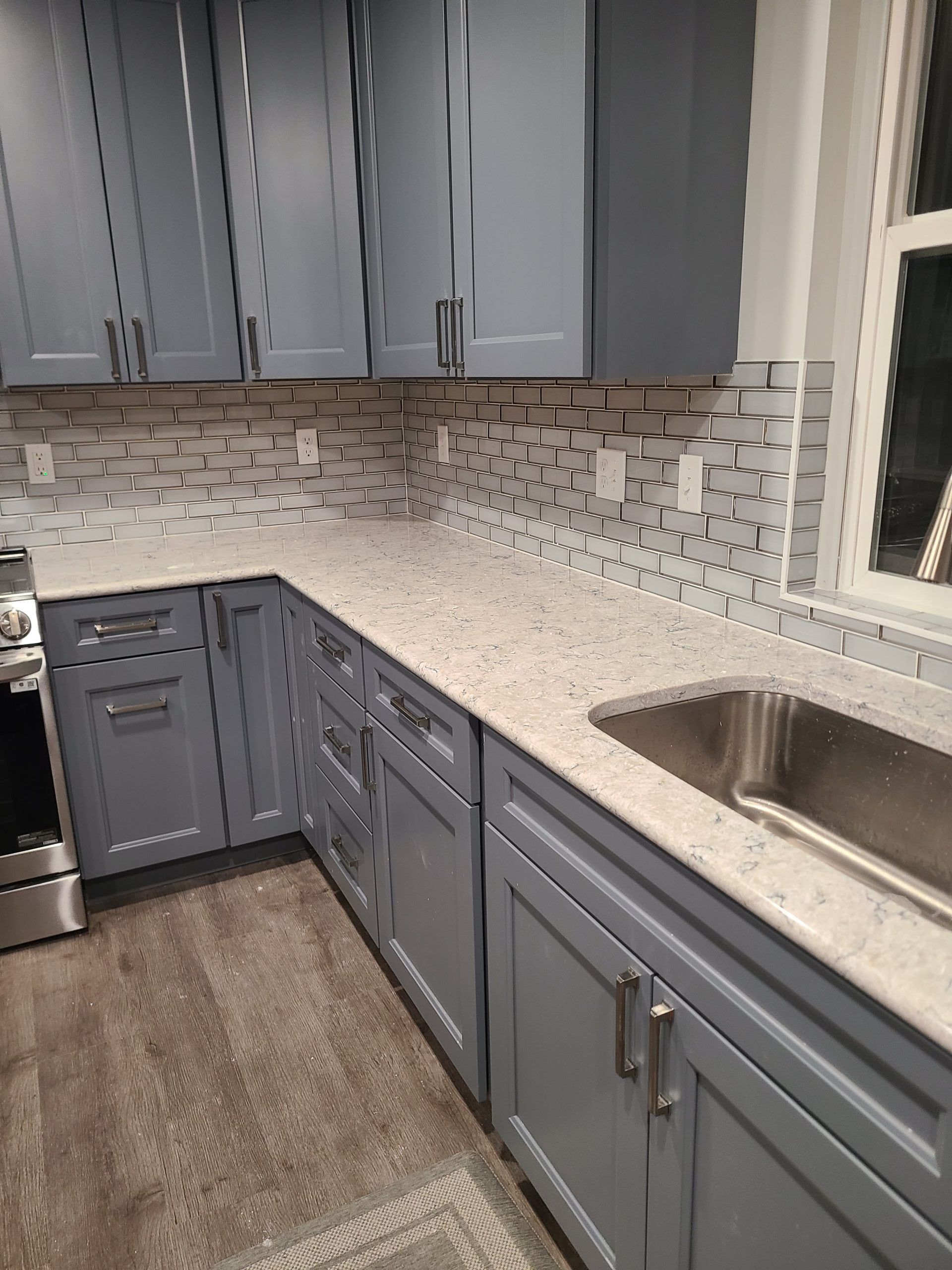 Blue kitchen cabinets and counters with a stainless steel sink.