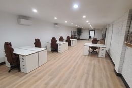 Office space with white desks, brown chairs, and a brick wall.