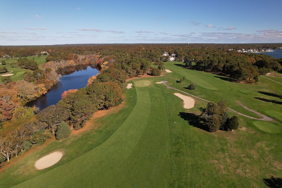 An aerial view of a golf course with a lake in the background.