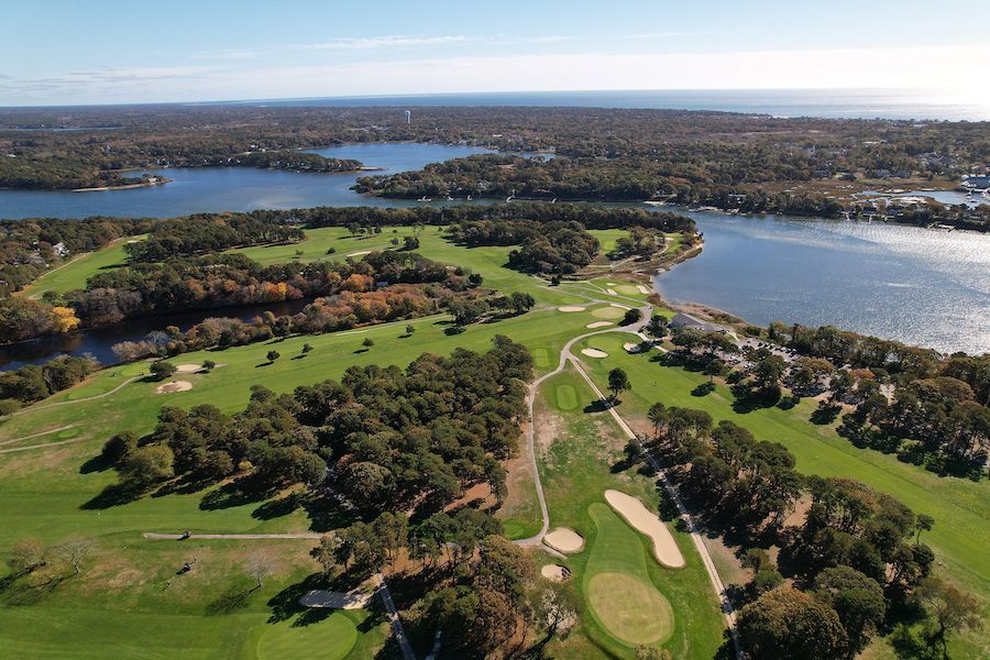 An aerial view of a golf course surrounded by trees and water