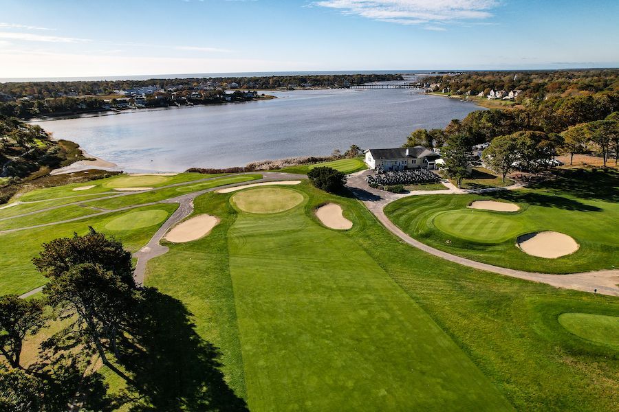 An aerial view of a golf course with a lake in the background.