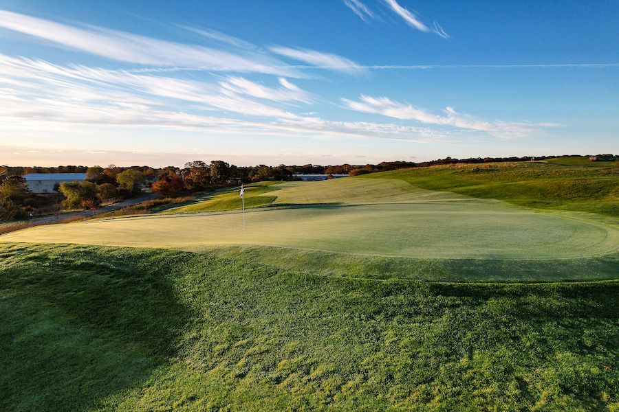 An aerial view of a golf course with a lake in the background.