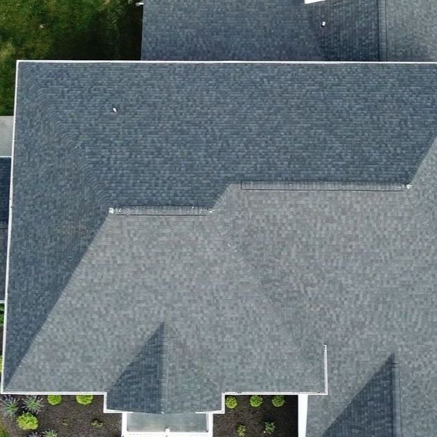 An overhead aerial view of a gray shingled residential roof with multiple peaks and sections.