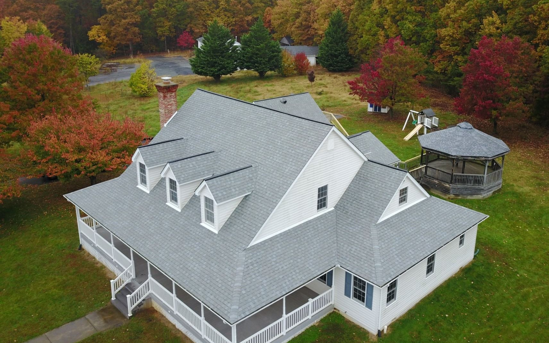 Recently completed roof installation done by Four Seasons Roofing with fall leaves in background
