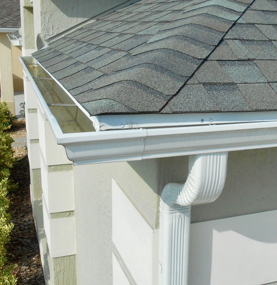 White gutters on a house with asphalt shingle roof.