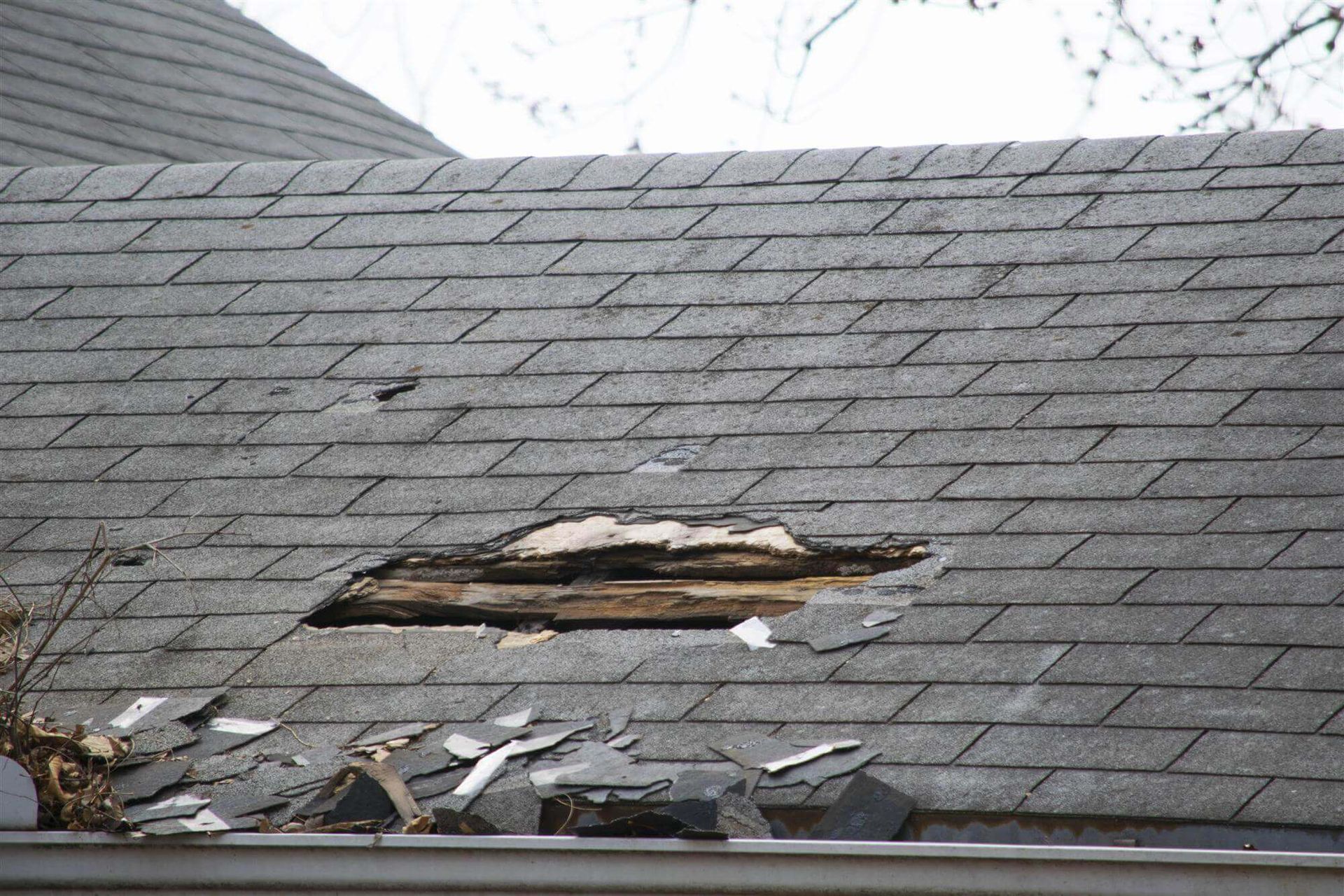 Severe roof damage on a Maryland home with missing shingles and exposed wood after a powerful storm, highlighting the risks of hidden storm damage
