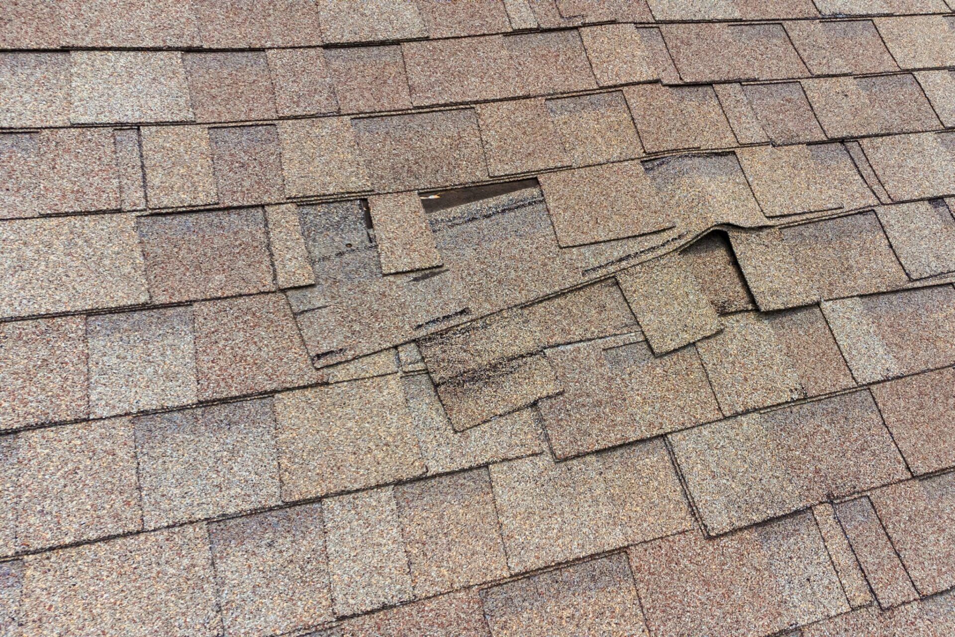 Residential roof with shingles separating and sliding off, potentially leading to a leak and roof repairs