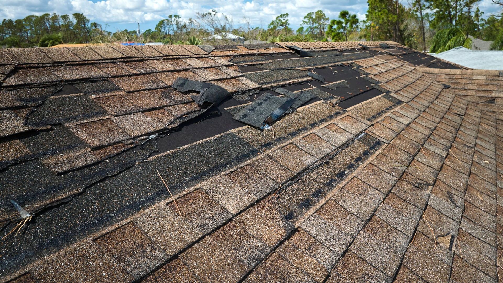 Residential roof in Maryland with missing shingles after a summer storm