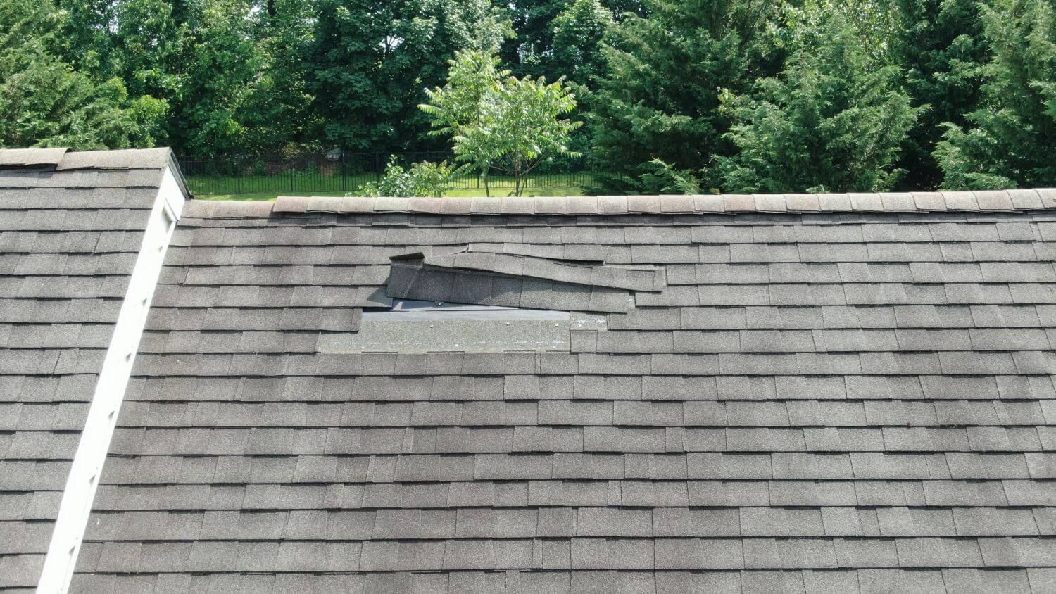 Roof shingles lifted and pulled up due to storm damage on a Maryland home
