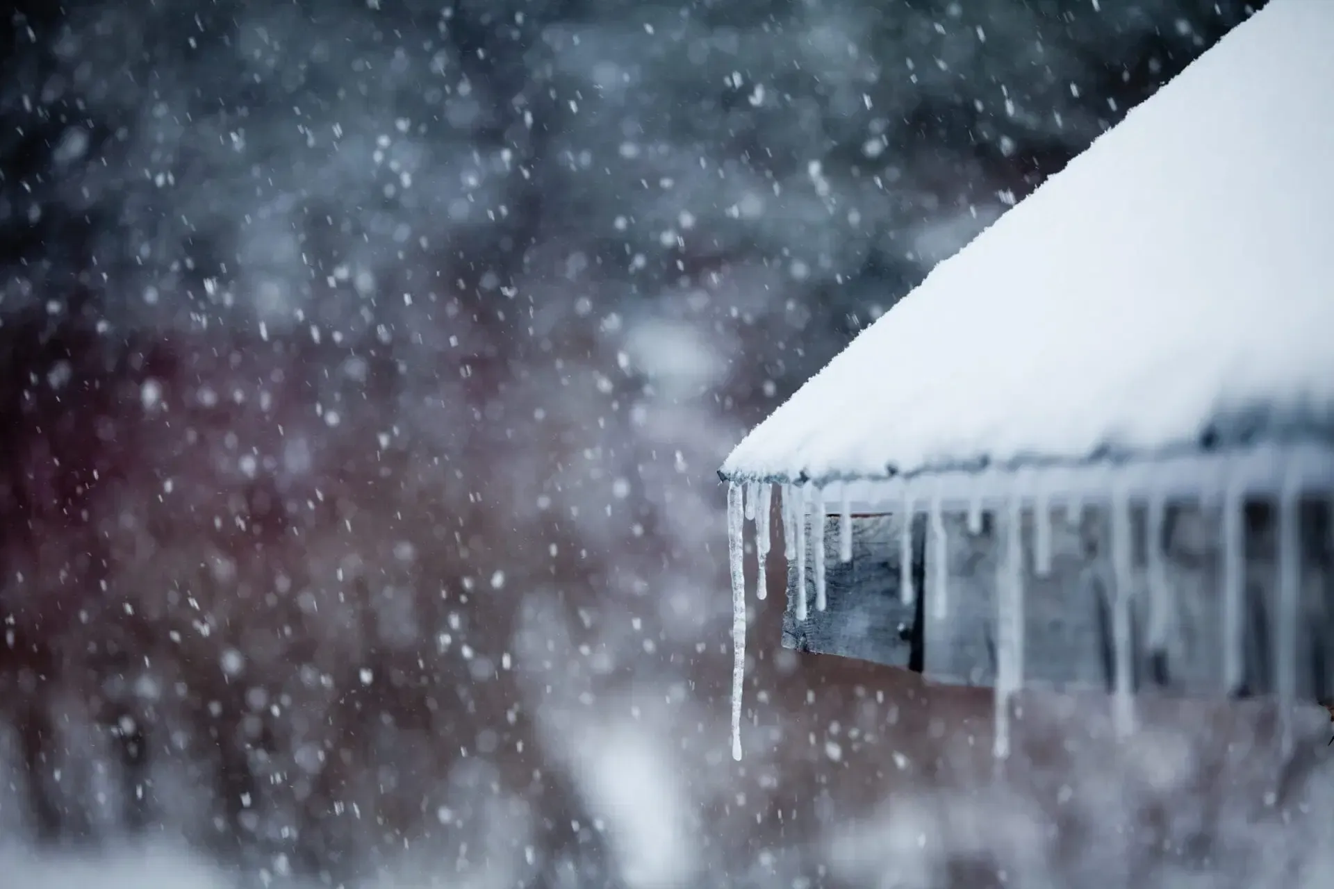 closeup of a roof during a winter storm with snow and ice building up