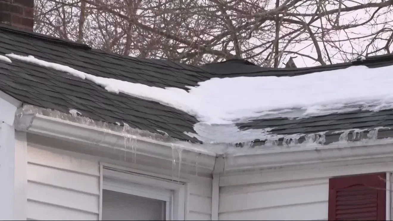 Snow-covered roof with icicles hanging from the gutters; exterior shot of a house.