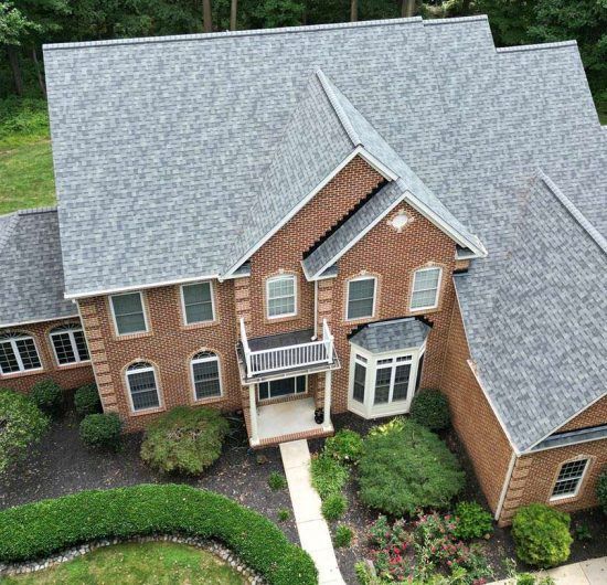 An aerial view of a large brick house with a gray roof.