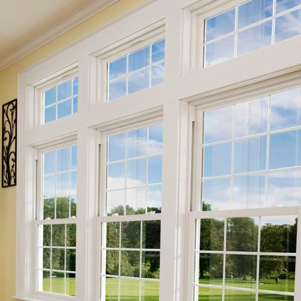 White framed windows with multiple panes, overlooking a grassy yard and blue sky.