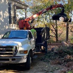 A white truck with a crane attached to the back is parked in front of a house.