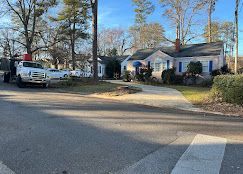 A white truck is parked on the side of the road in front of a house.