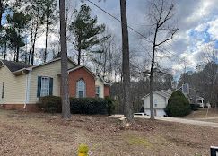 There is a fire hydrant in front of a house in the woods.