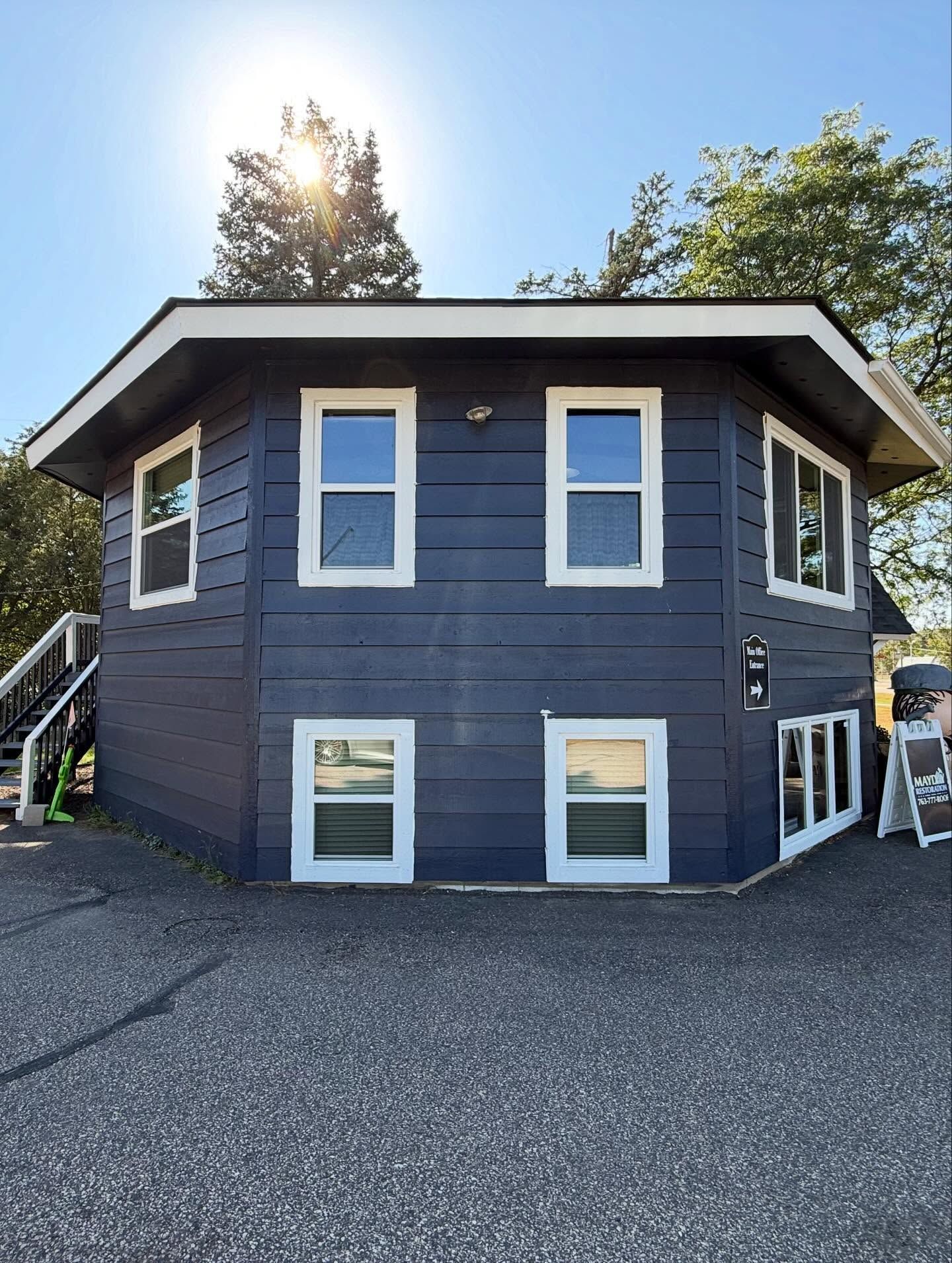 Blue, octagonal building with white-framed windows, against a bright sky.