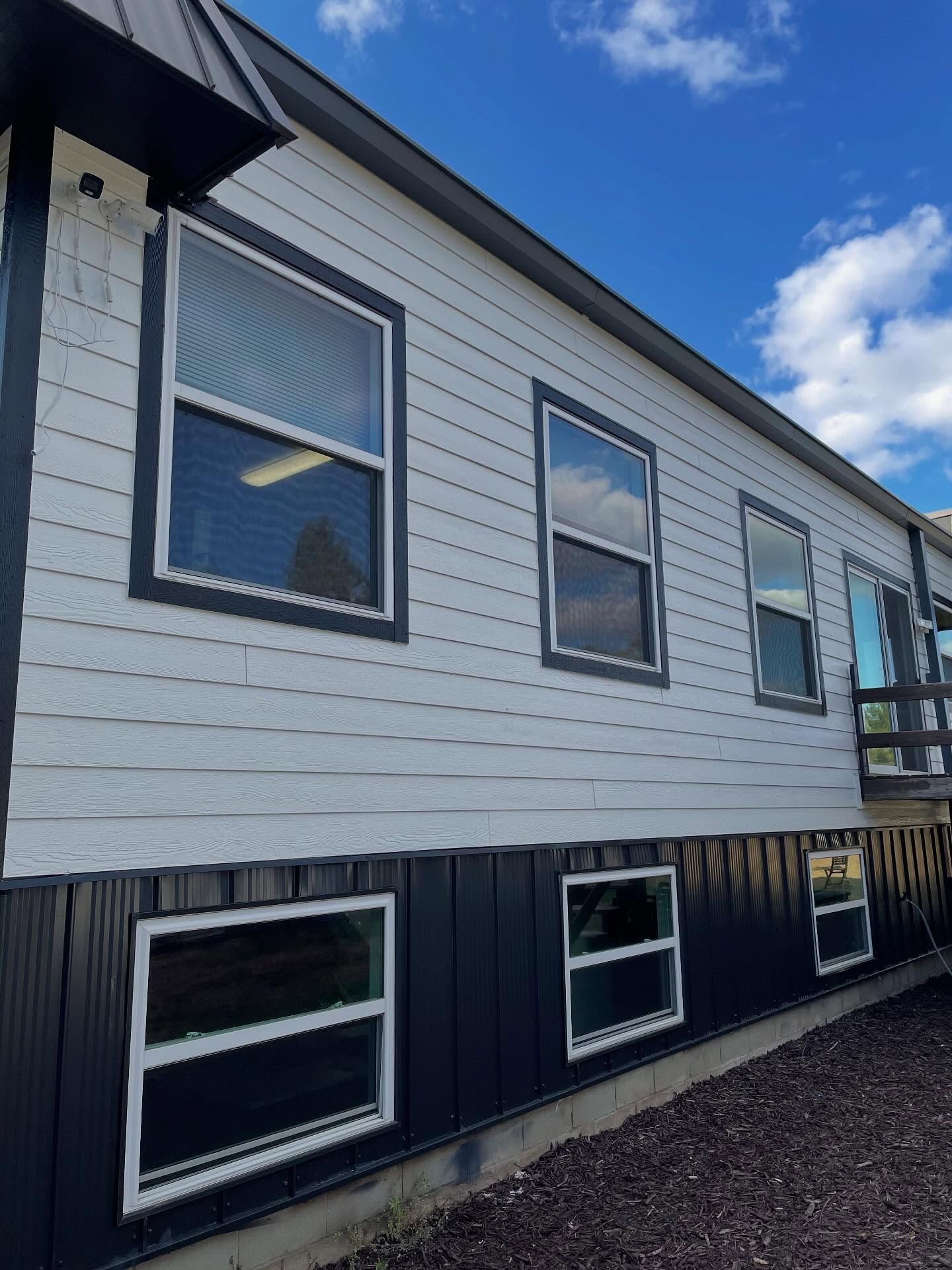 White and black building with multiple windows against a blue sky, gravel path in the foreground.