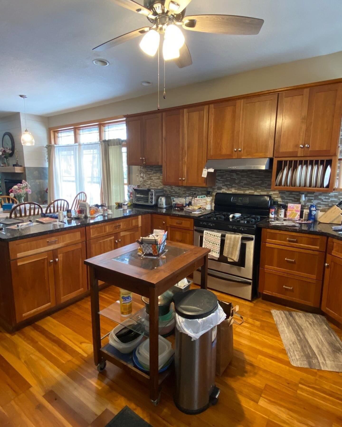 A kitchen with wood cabinets, a gas range, and a center island. Sunlight streams in from a window behind the island.