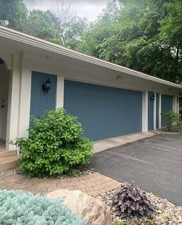 Exterior view of a house with a blue garage door, white trim, and landscaping in front.