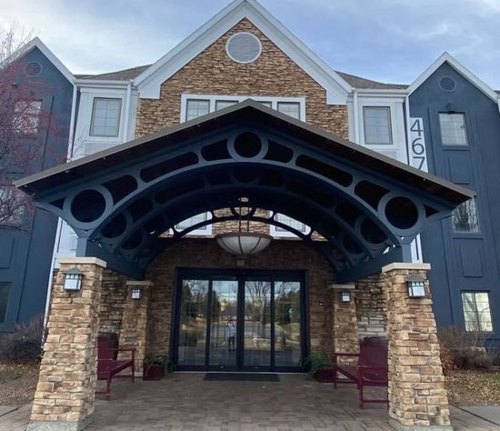 Hotel entrance with a covered entryway. Stone pillars support a dark blue canopy.