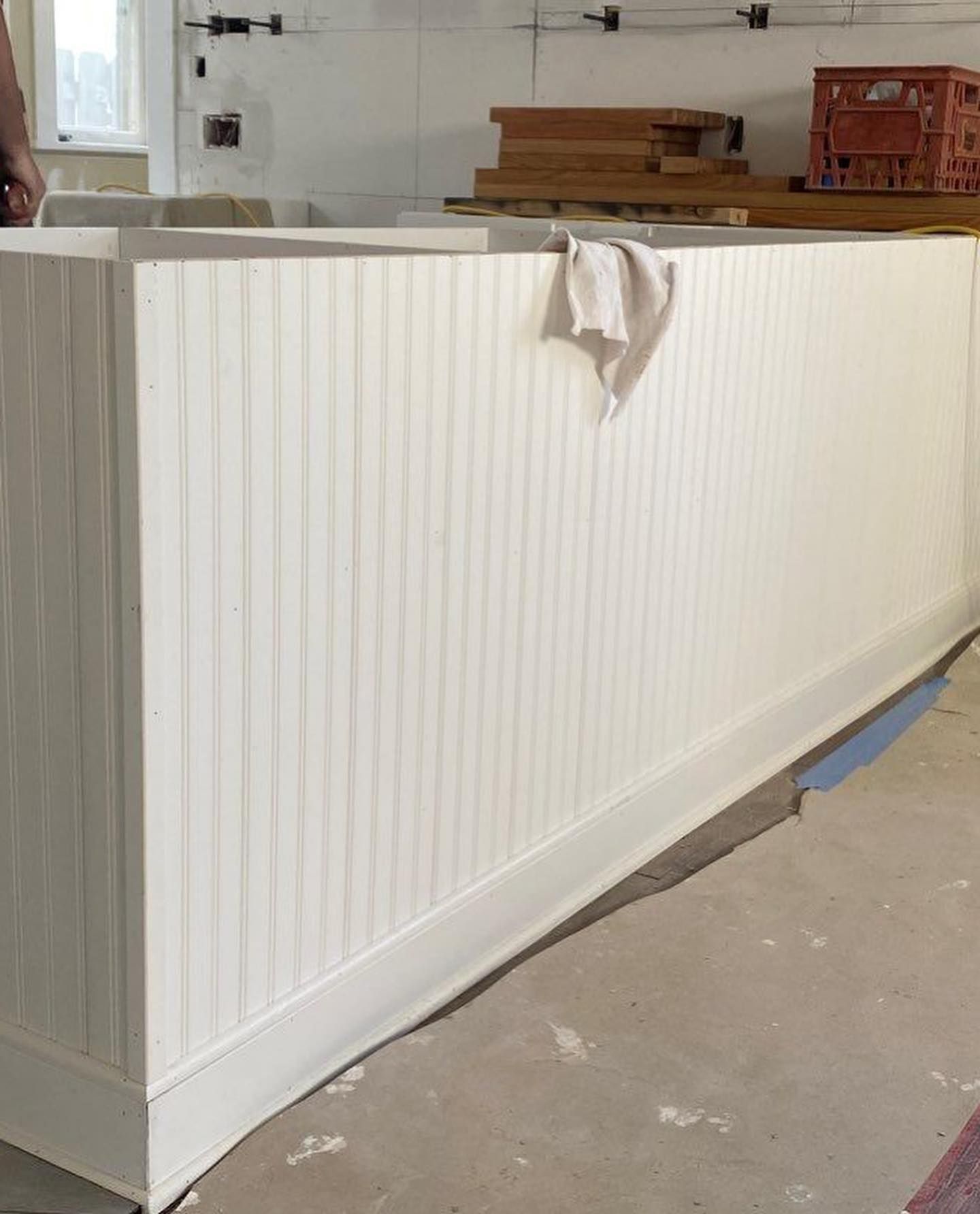 White beadboard paneling forming a bar or counter in a room under construction, with a rag hanging on it.