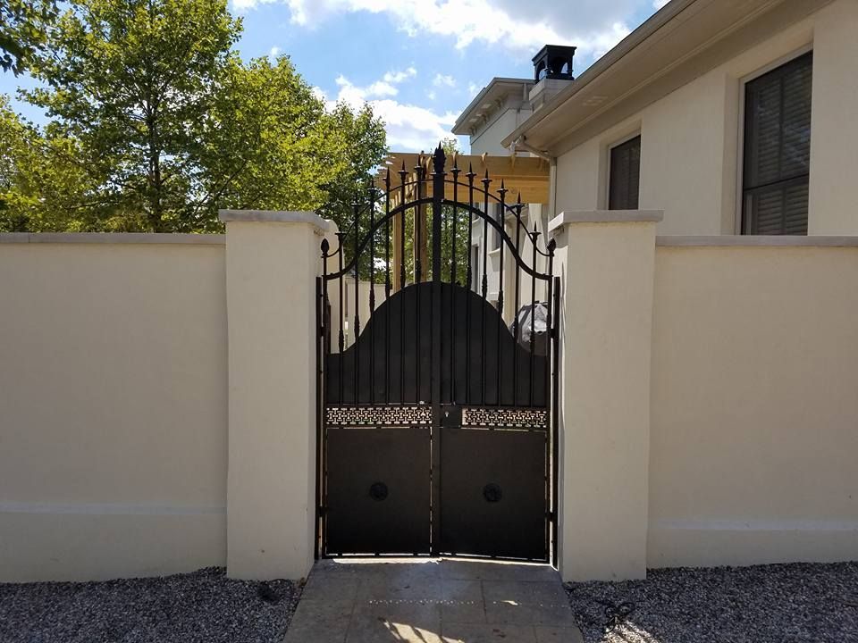 A wrought iron gate leading to a white house