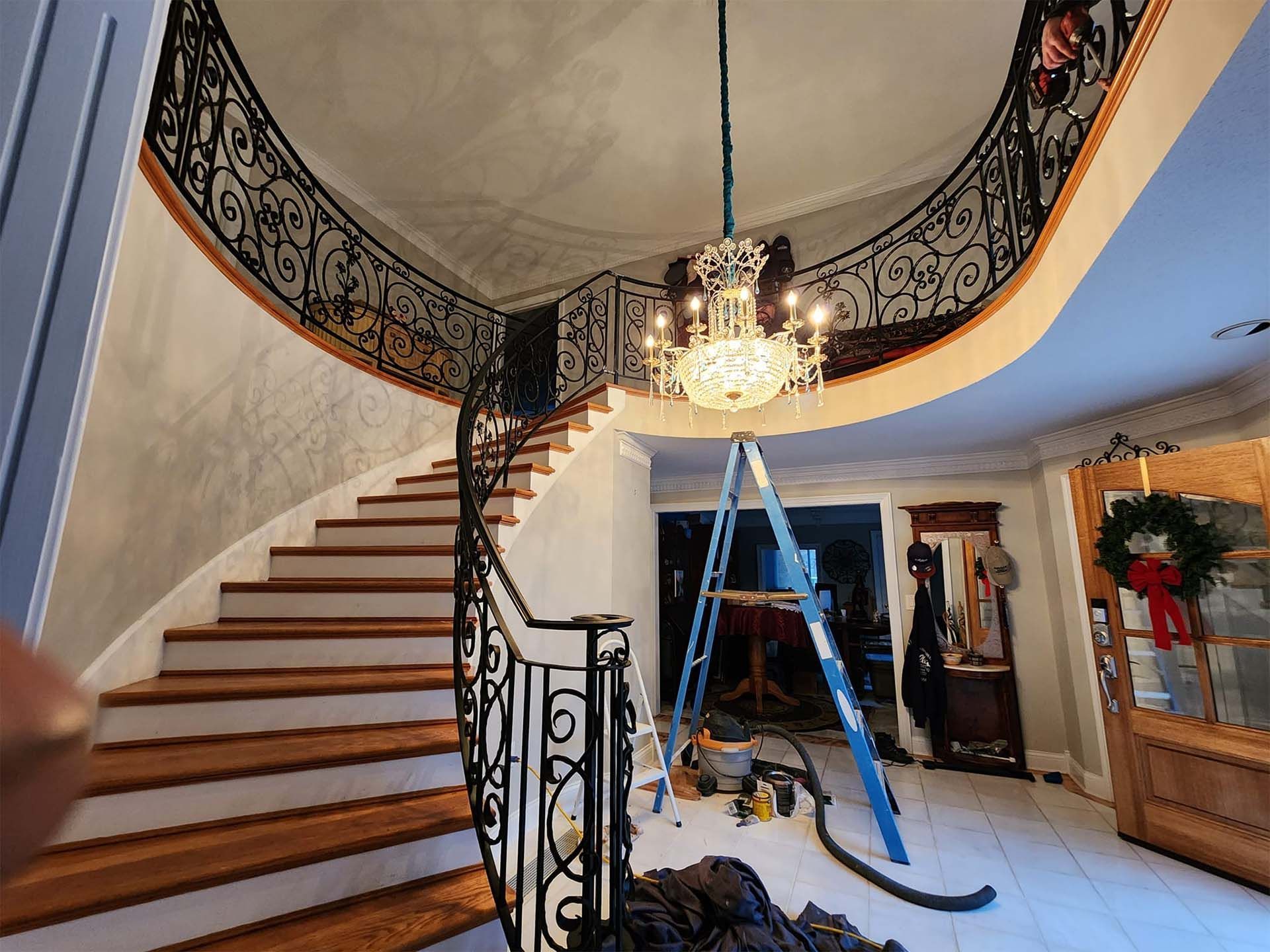 A spiral staircase with a wrought iron railing and a chandelier hanging from the ceiling