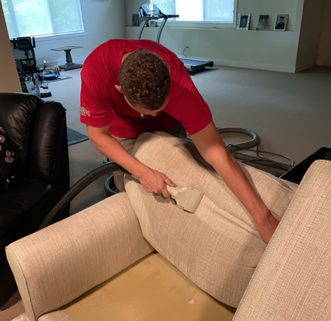 Worker steam cleaning upholstery