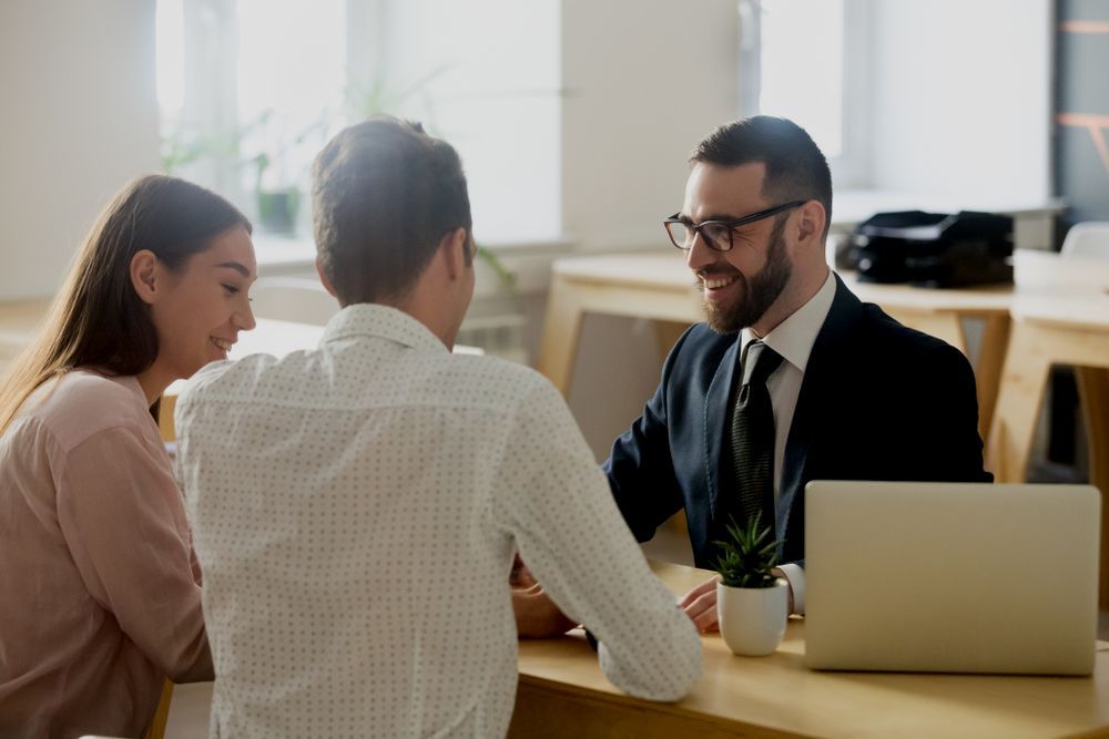 A Man And A Woman Are Sitting At A Table Talking To A Man In A Suit — Charlestown Law Firm In Lake Macquarie, NSW