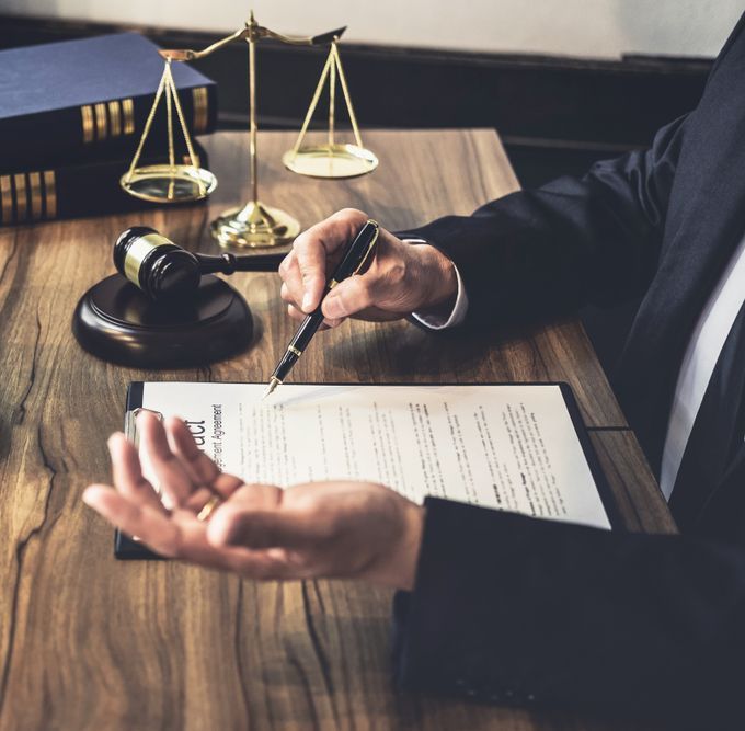 A Man In A Suit Is Signing A Document With A Pen — Charlestown Law Firm In Charlestown, NSW