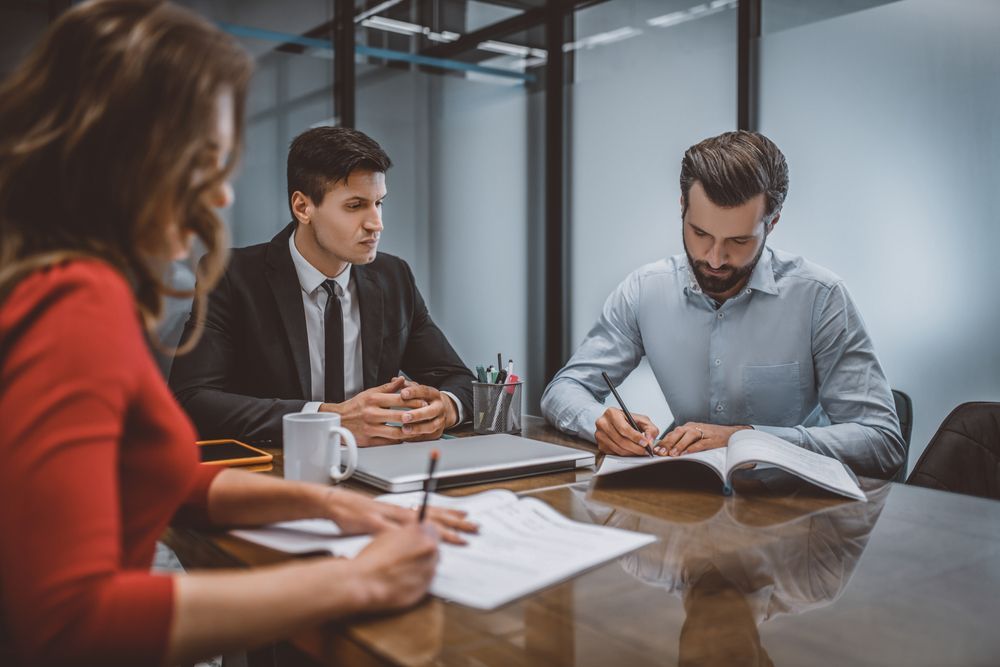 A Group Of People Are Sitting At A Table Having A Meeting — Charlestown Law Firm In Port Stephens, NSW
