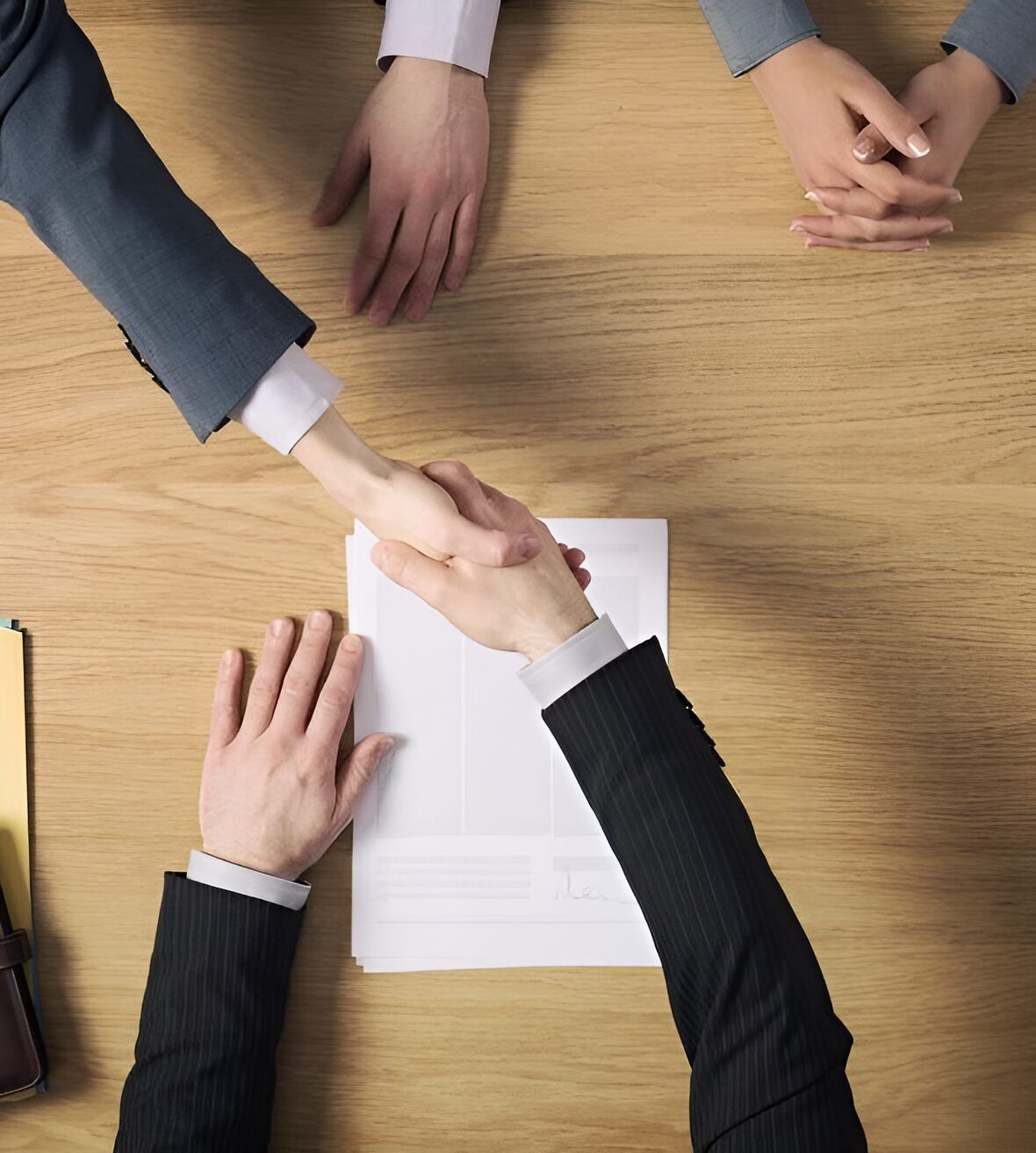 A Group Of People Shaking Hands Over A Piece Of Paper — Charlestown Law Firm In Sydney, NSW