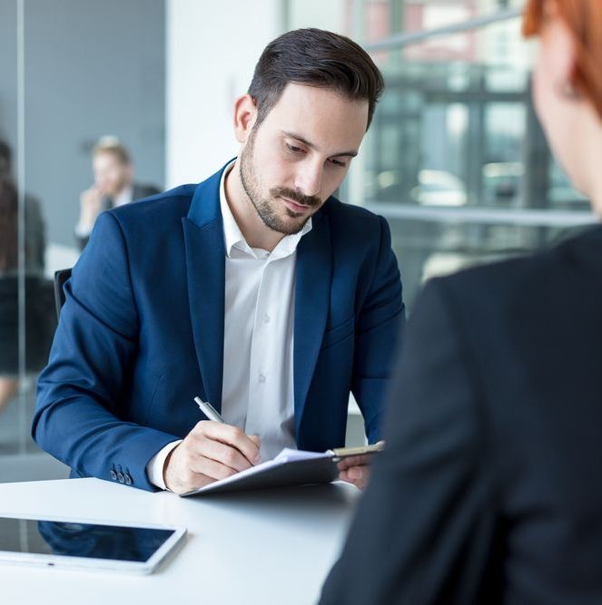 A Man In A Blue Suit Is Writing On A Piece Of Paper — Charlestown Law Firm In Central Coast, NSW