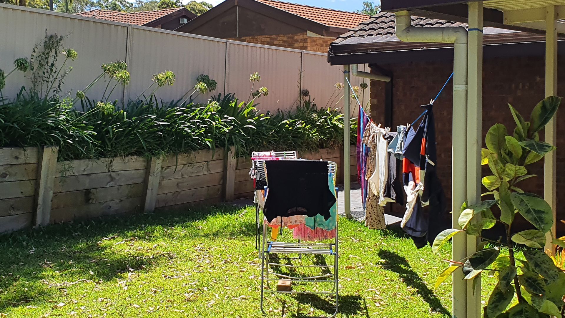 Clothes are hanging on a clothes line in a backyard.