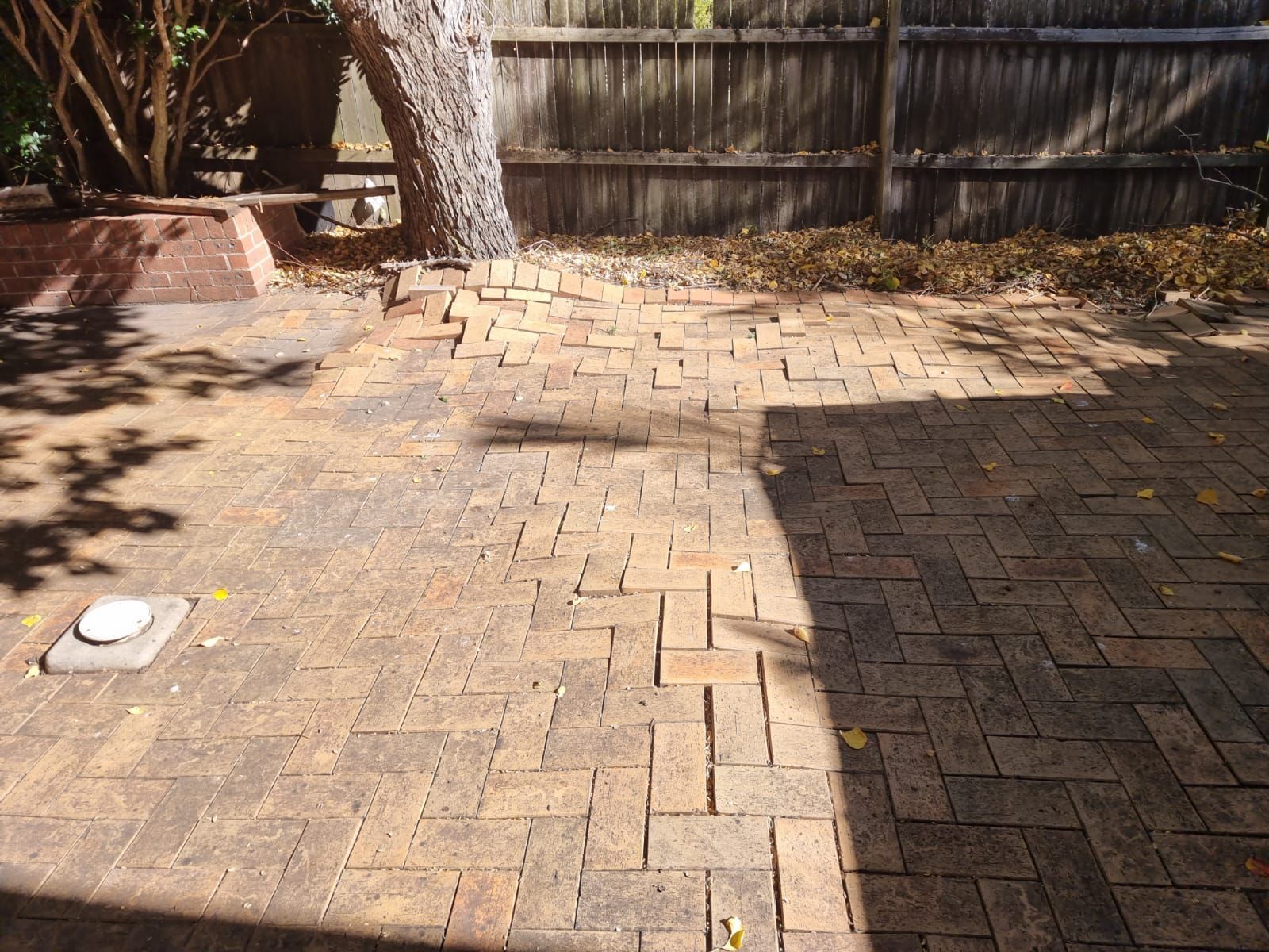 A brick patio with a wooden fence in the background