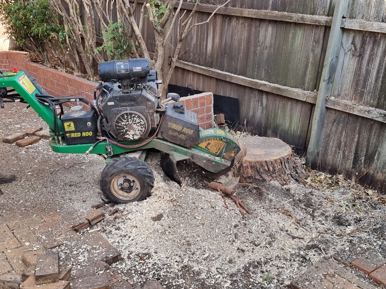 A stump grinder is cutting a tree stump in a backyard.