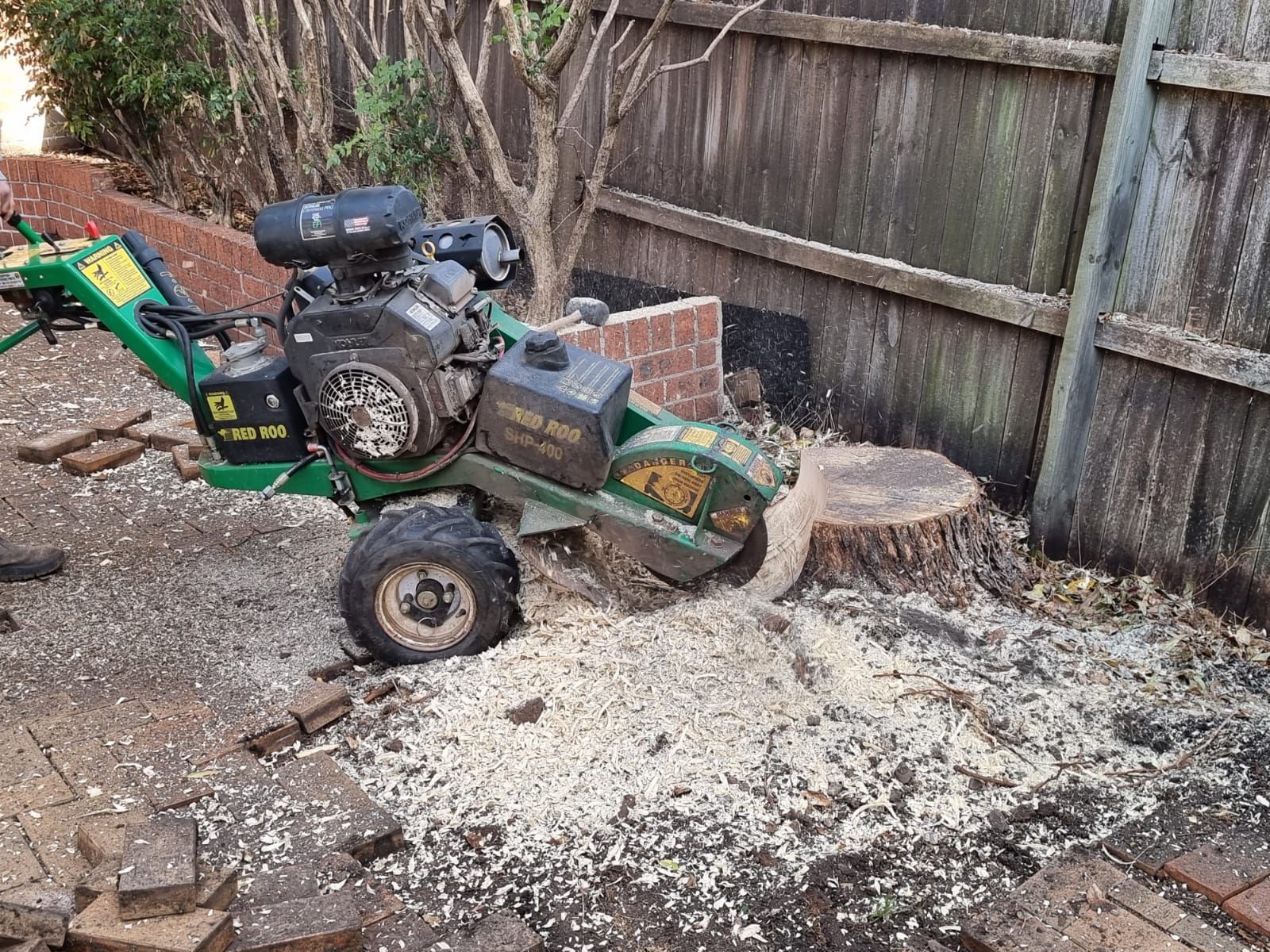 A stump grinder is cutting a tree stump in a backyard.