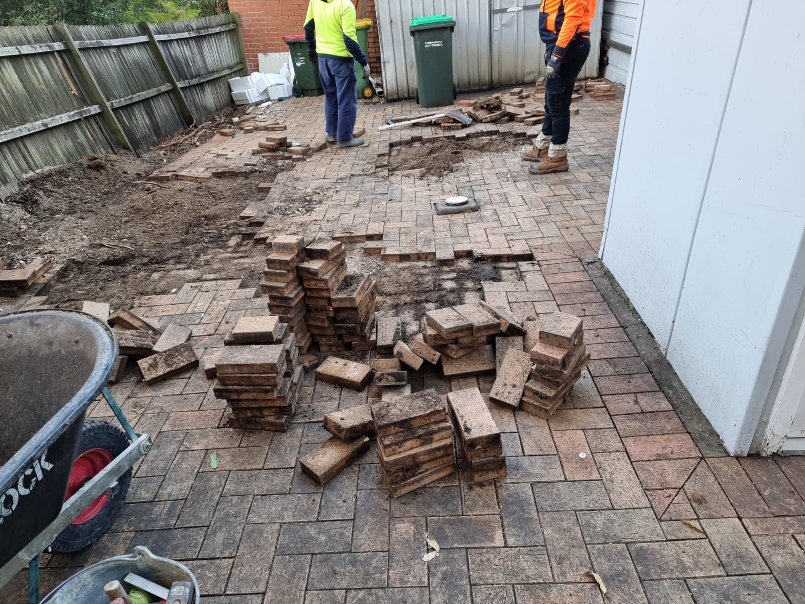 A group of people are working on a brick patio.