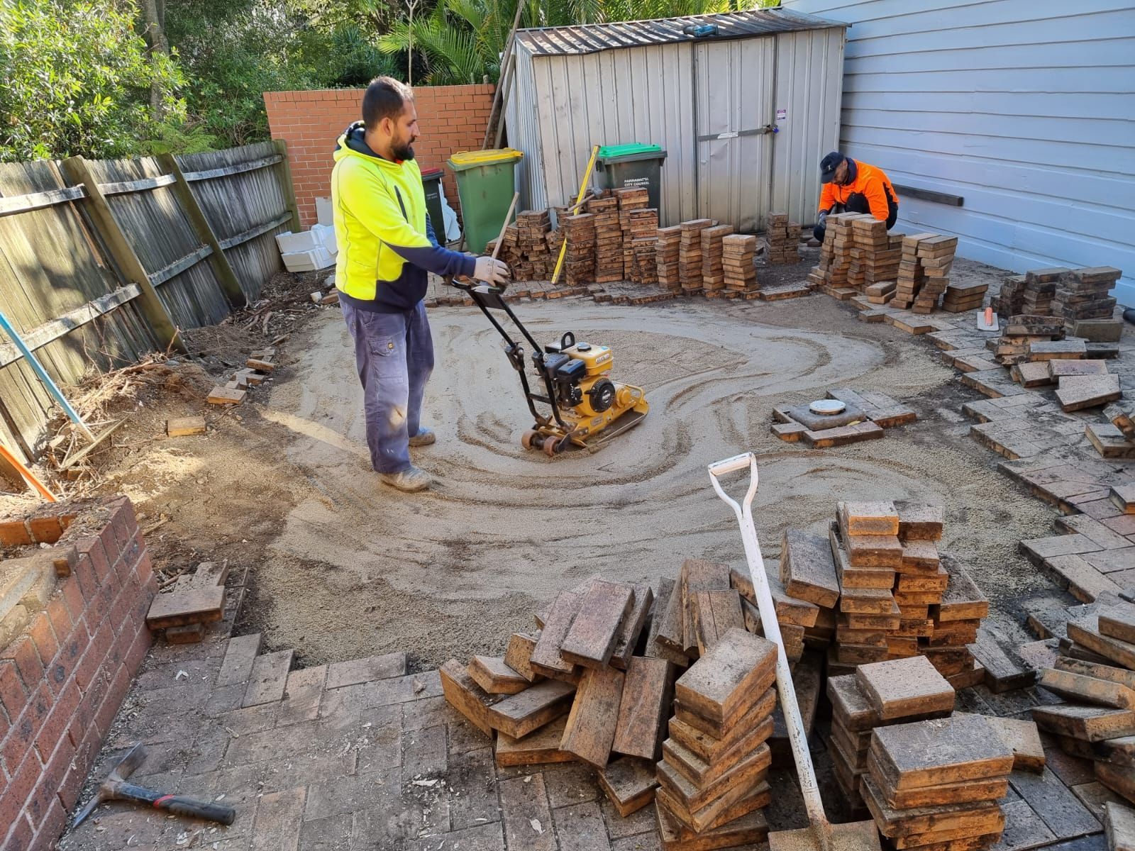 A man is using a machine to level the ground in a backyard.