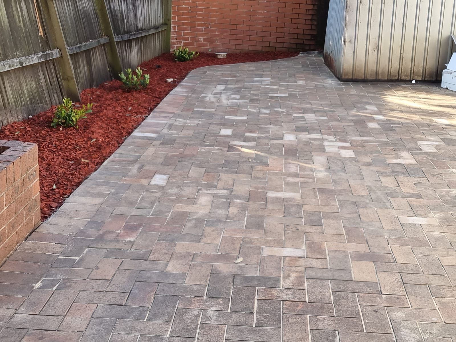 A brick patio with a fence in the background