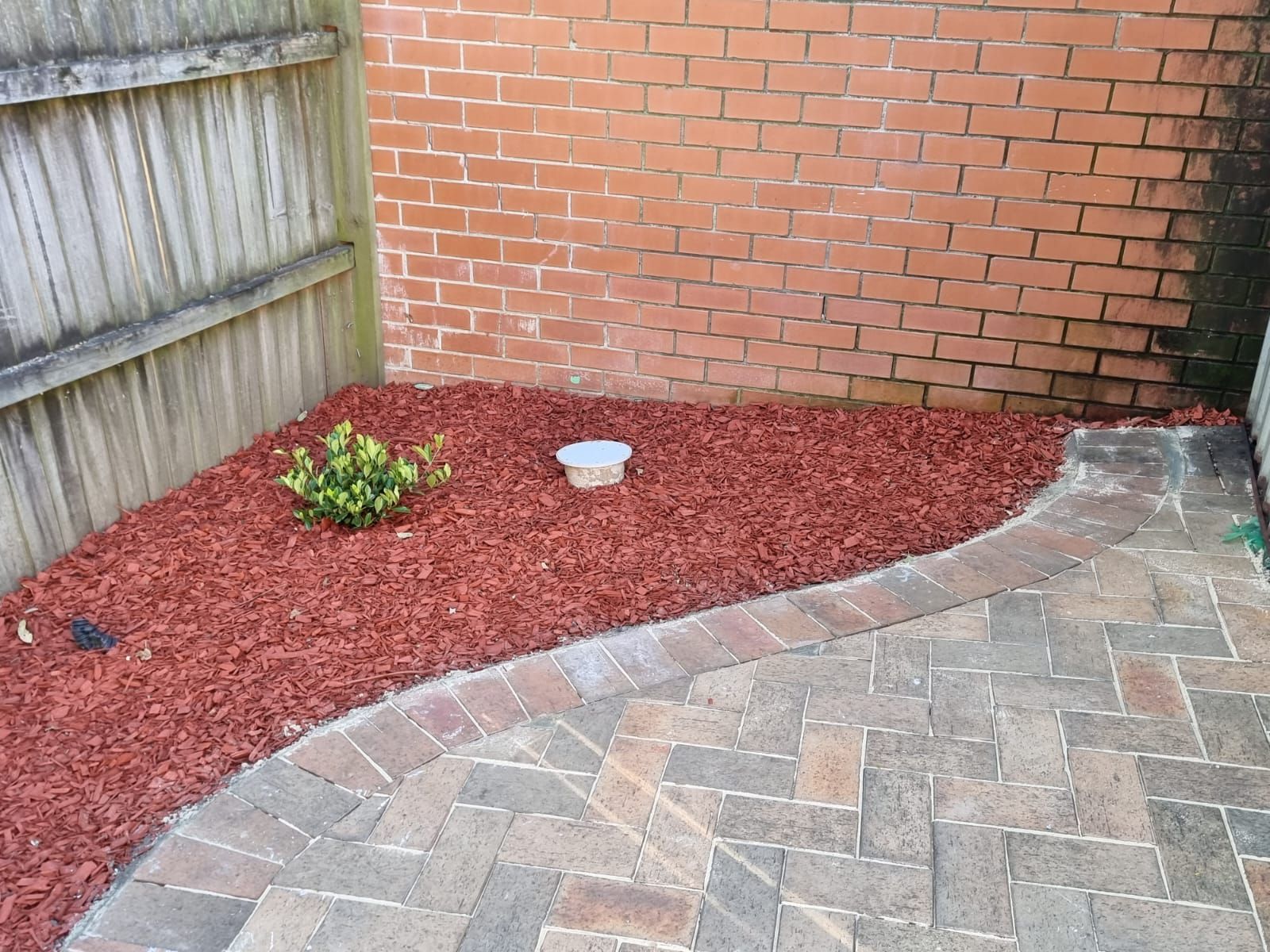 A brick patio with red mulch and a brick wall