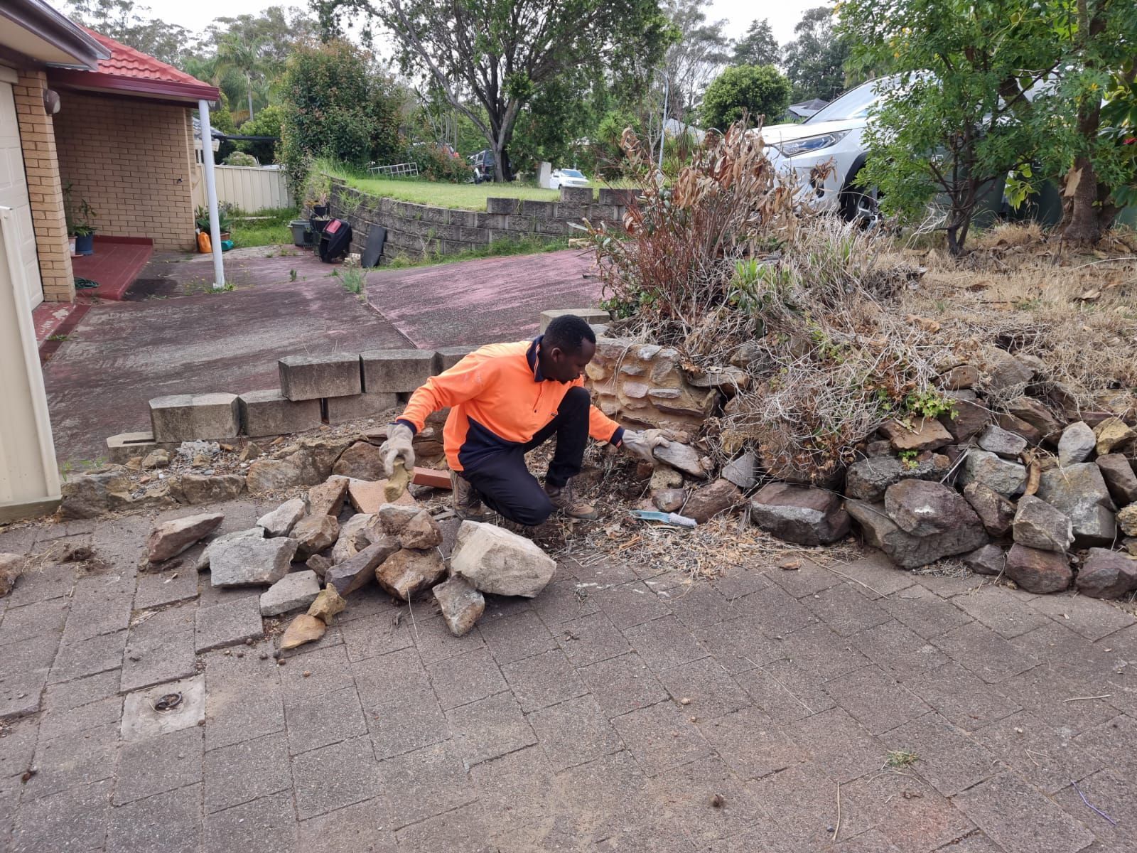 A man is kneeling down in front of a pile of rocks.