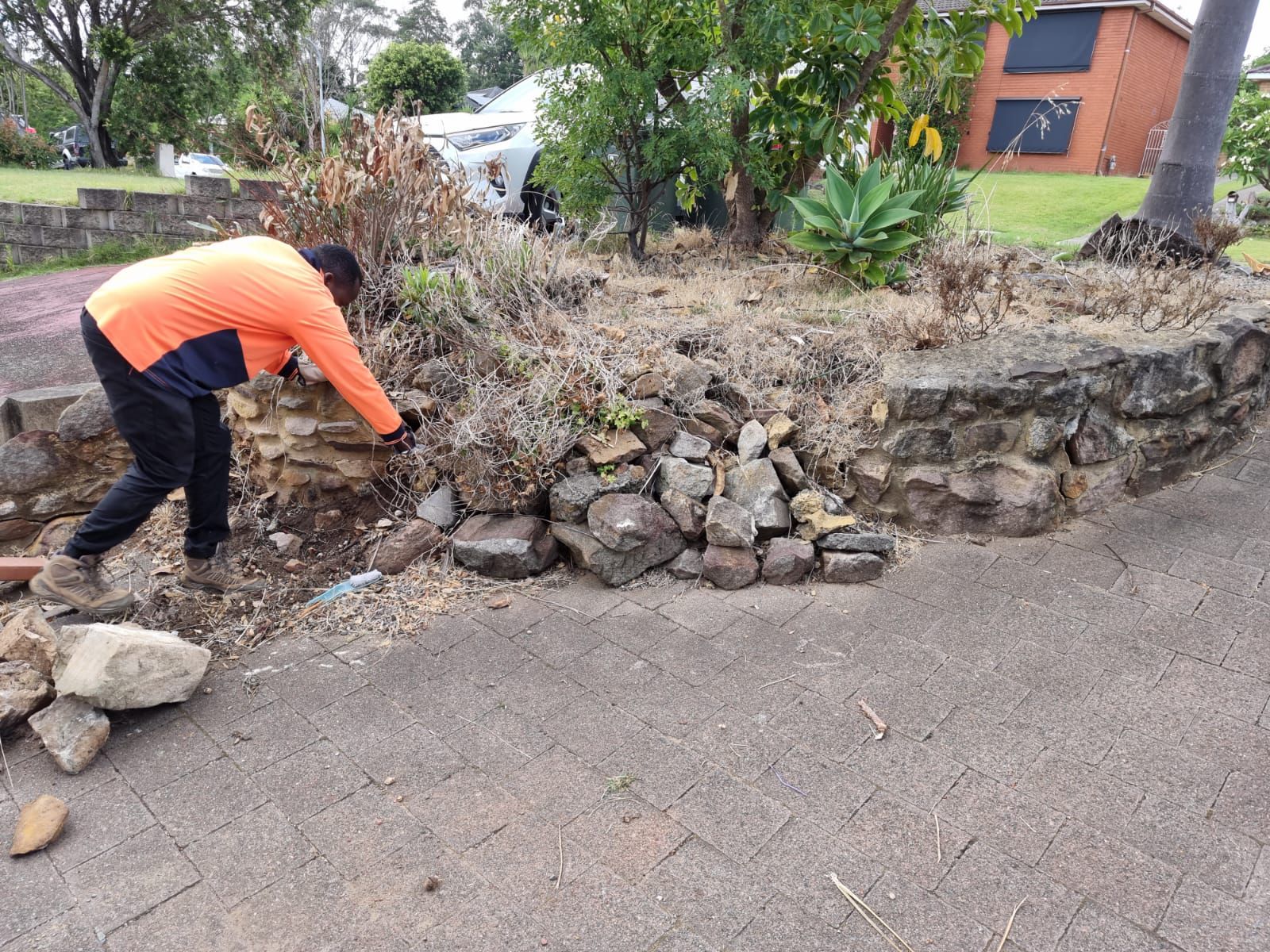 A man is working on a stone wall in a garden.