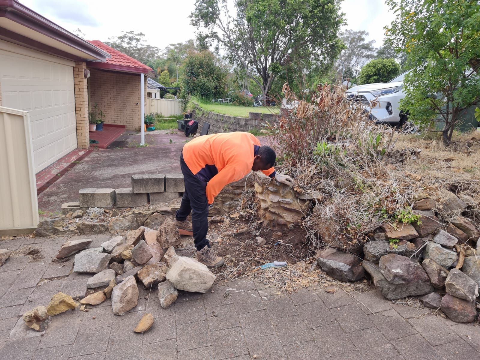 A man is working on a rock wall in front of a house.