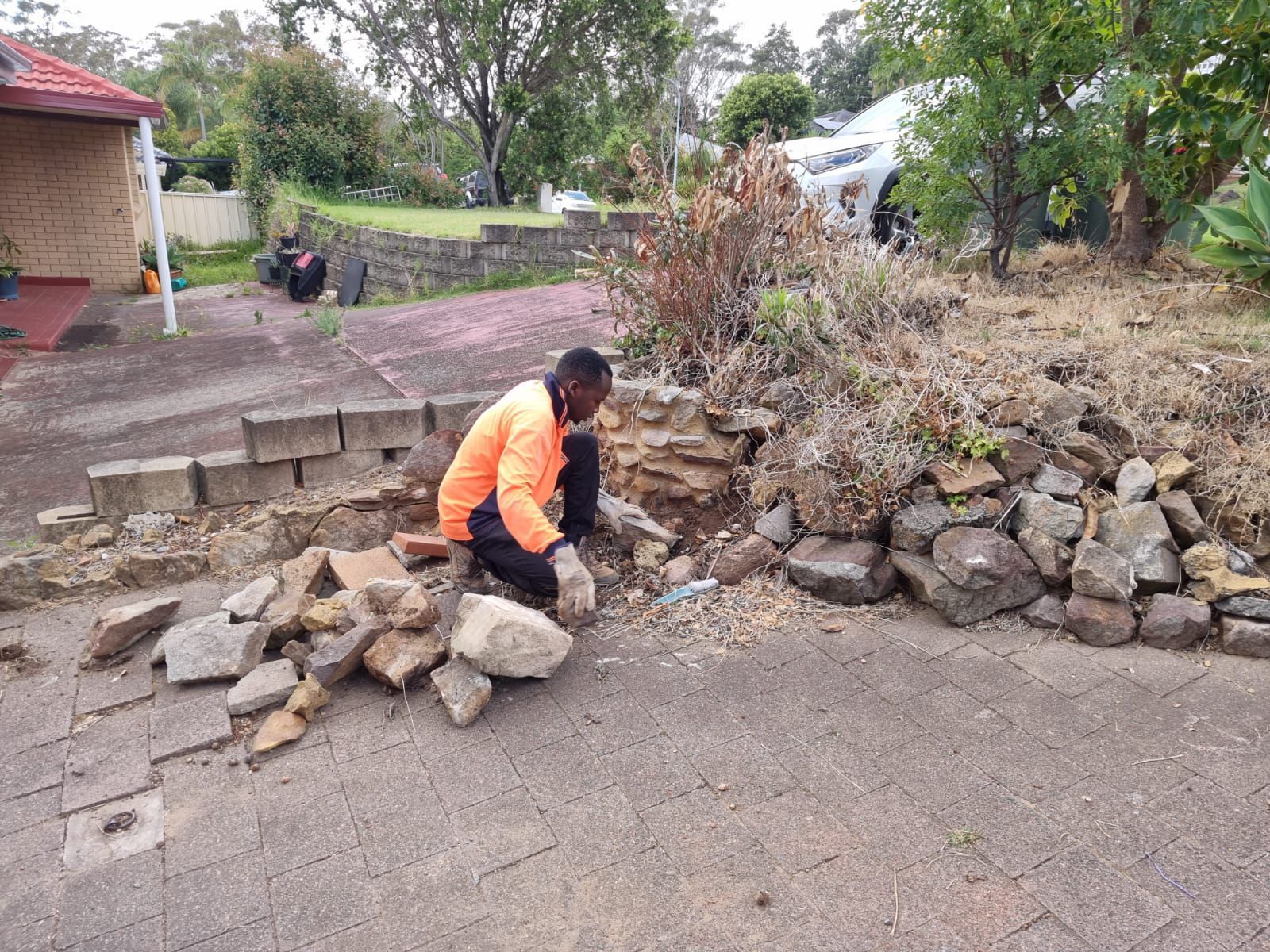 A man is kneeling down in front of a pile of rocks.