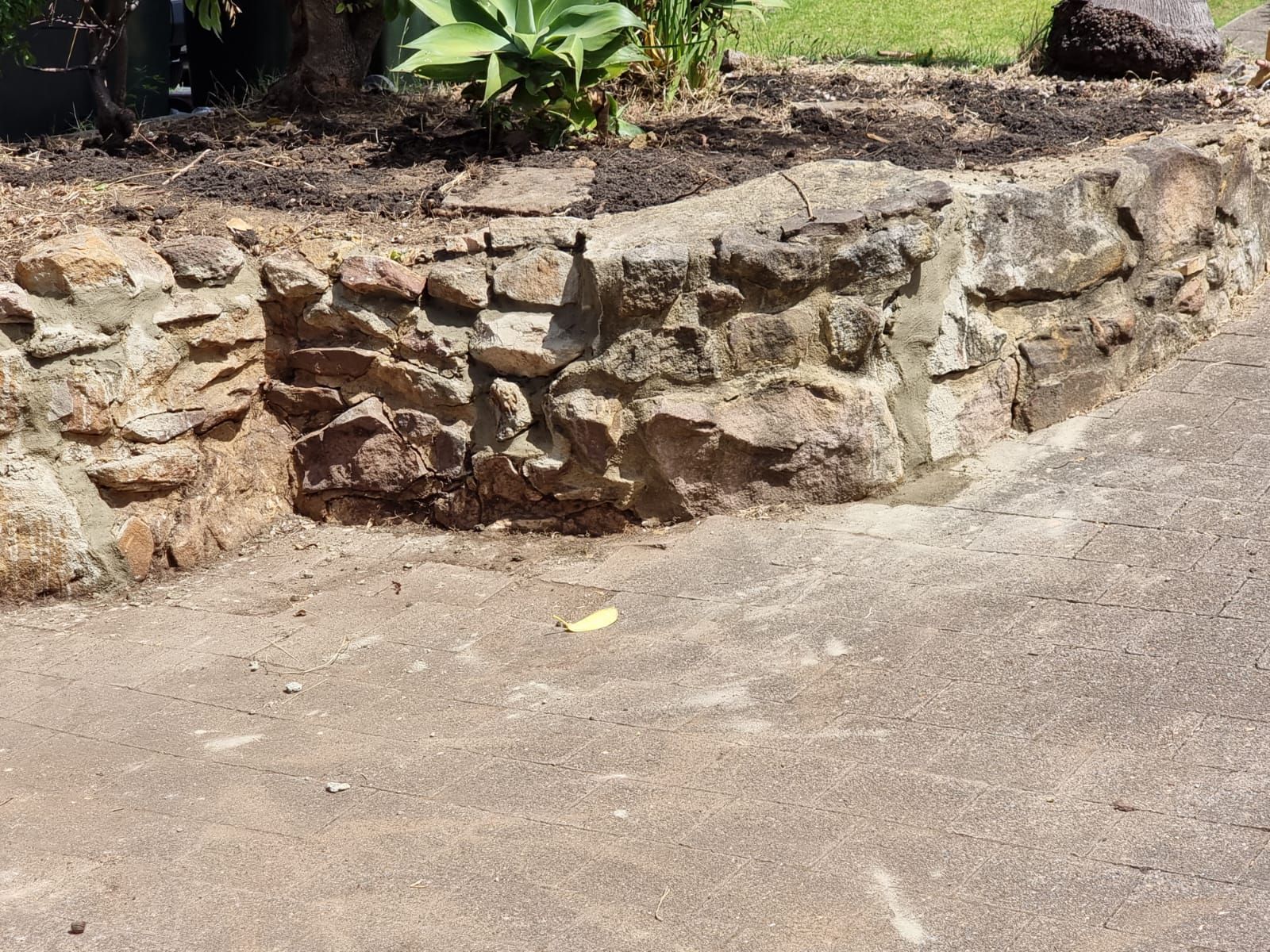 A stone wall is sitting on the side of a road.