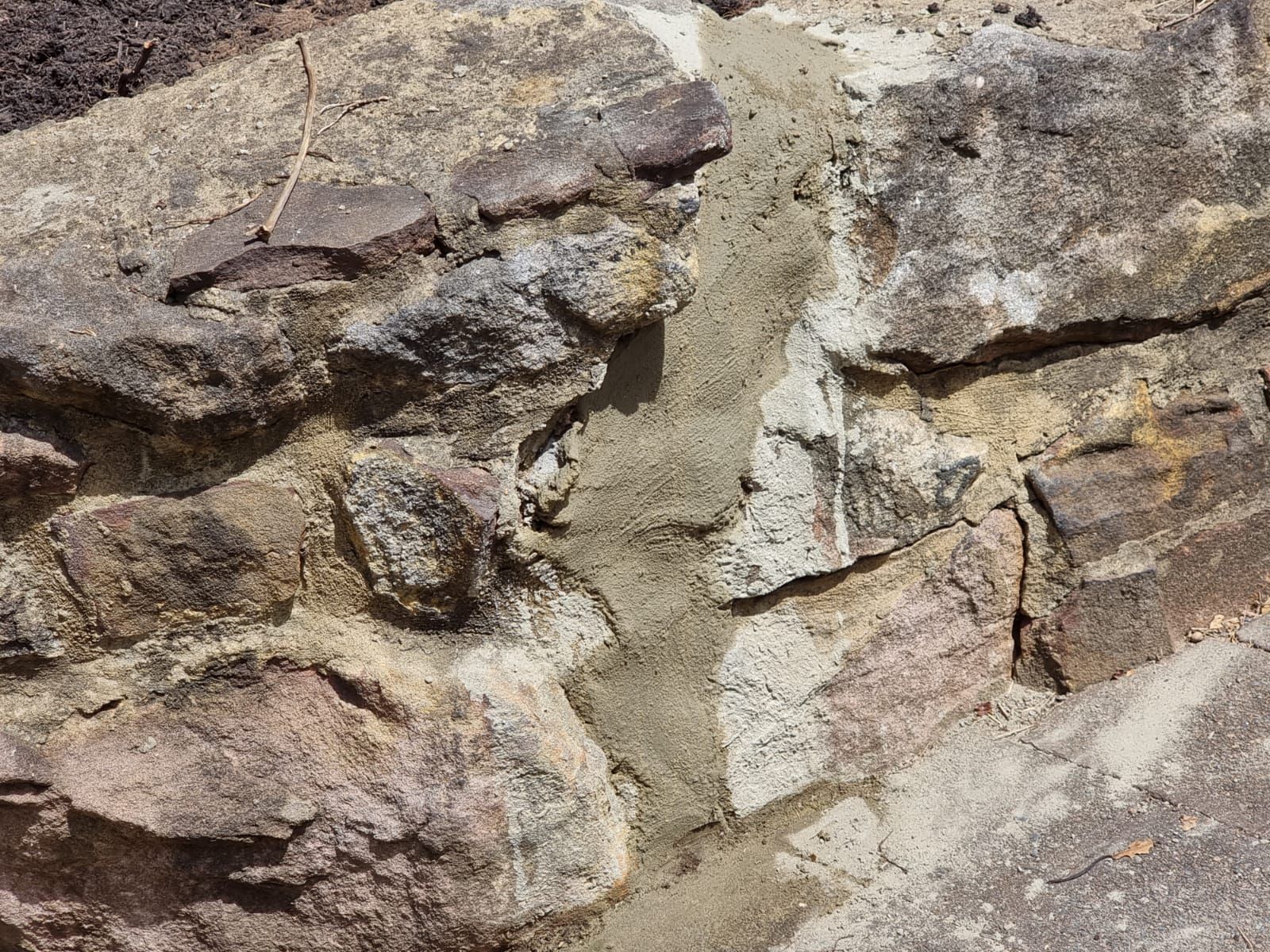 A close up of a stone wall with concrete being applied to it.